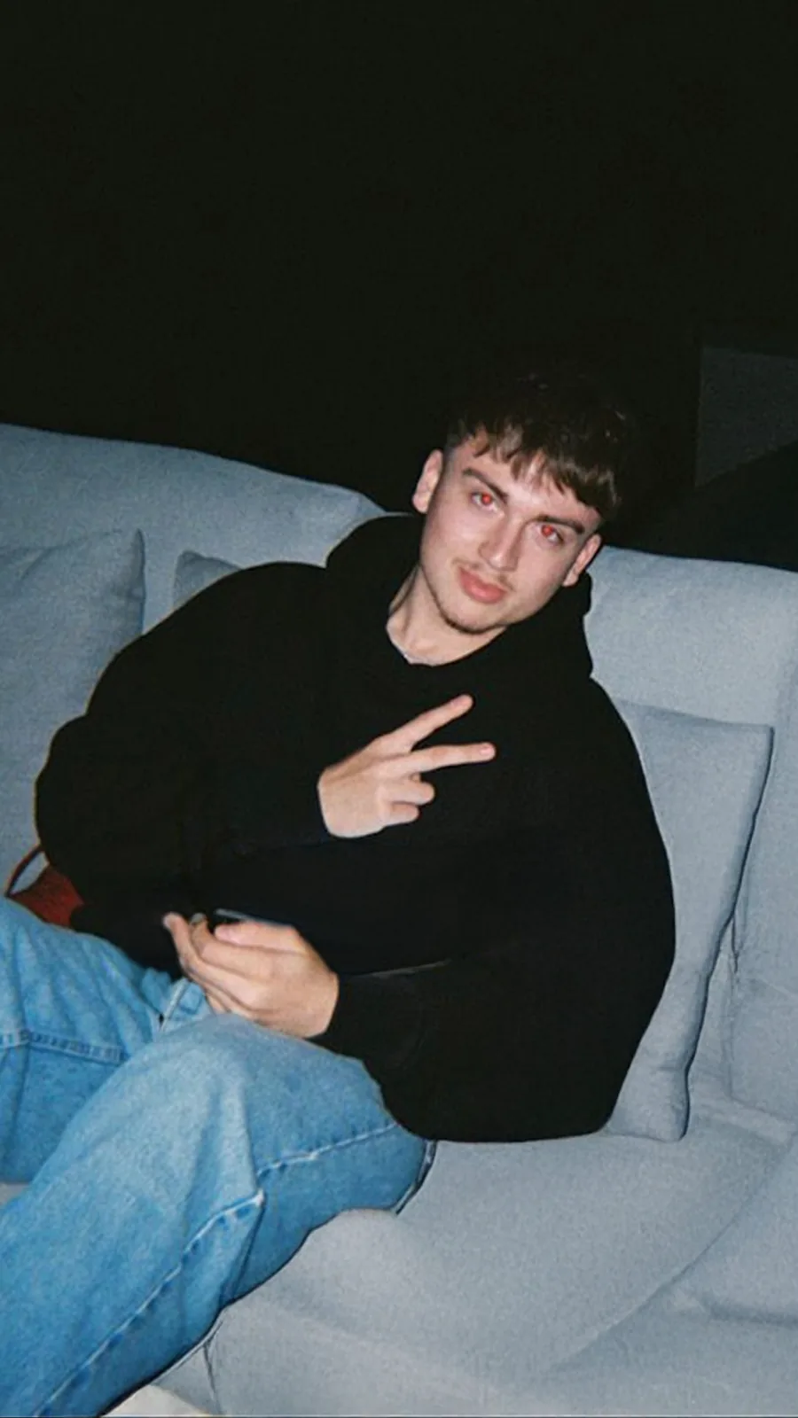 Rafa Villaseñor on a sofa at night in a black hoodie, lit by camera flash.