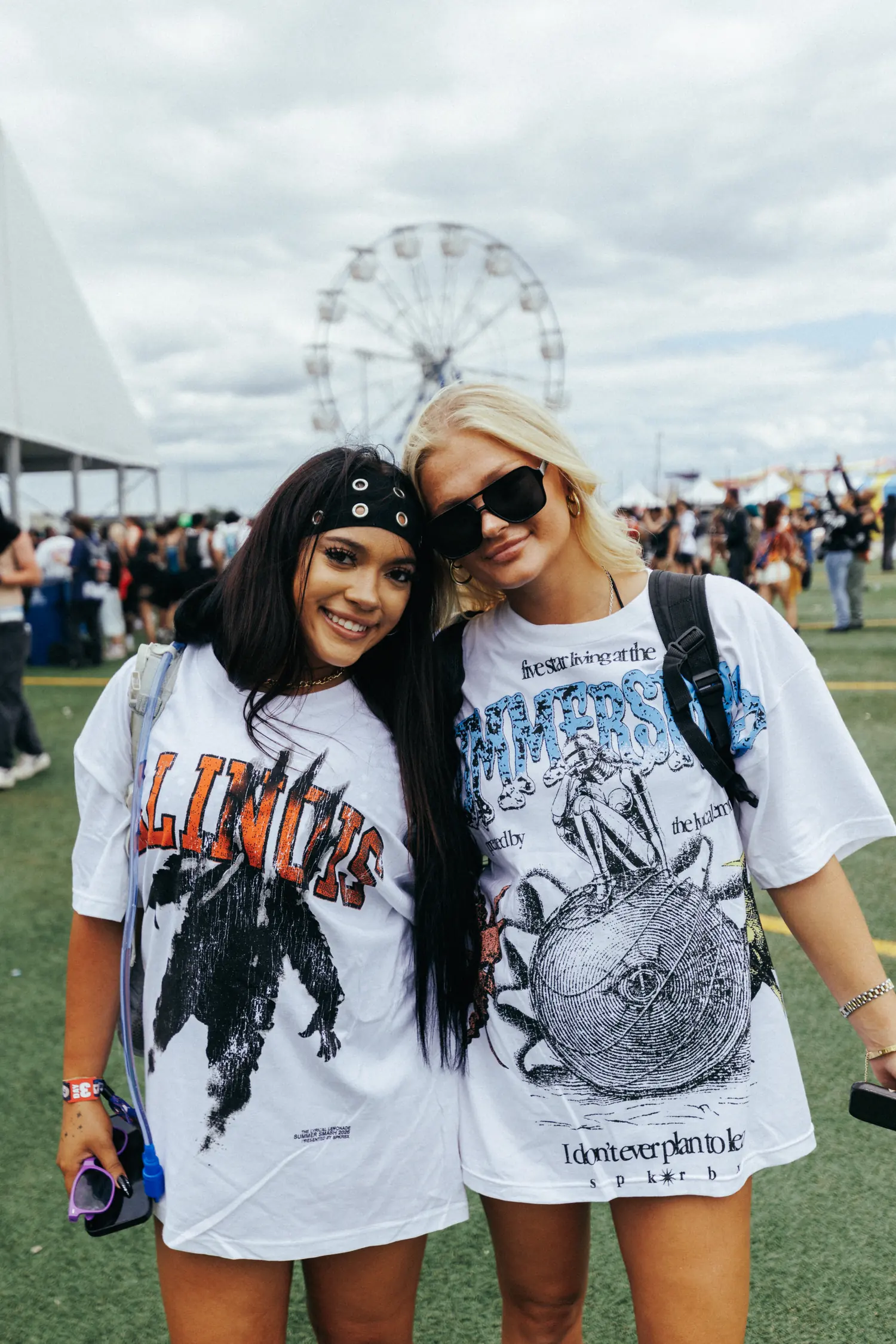 Two attendees in festival tees, the wheel behind them