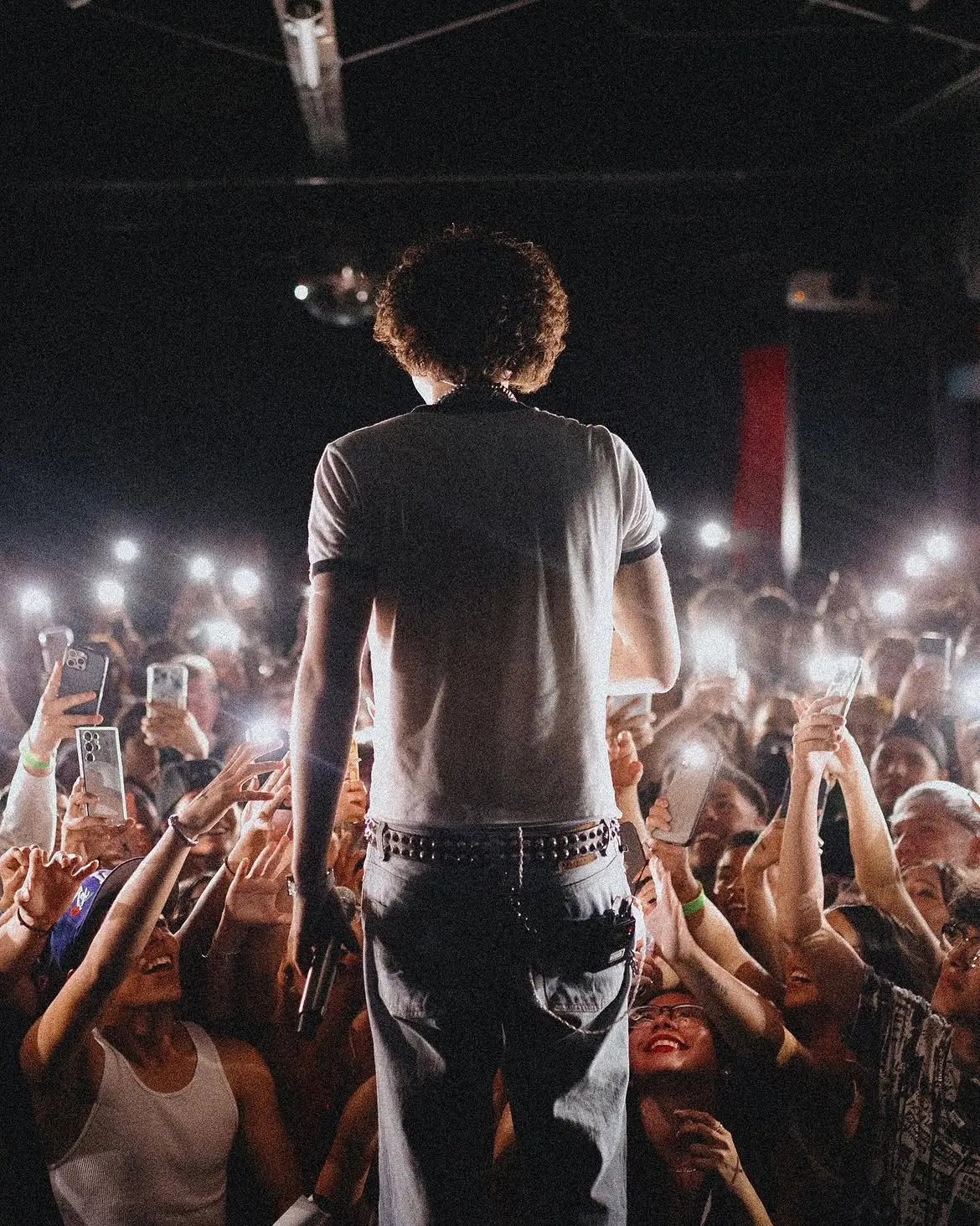 El Paso, from behind the artist — the room lit by phone screens