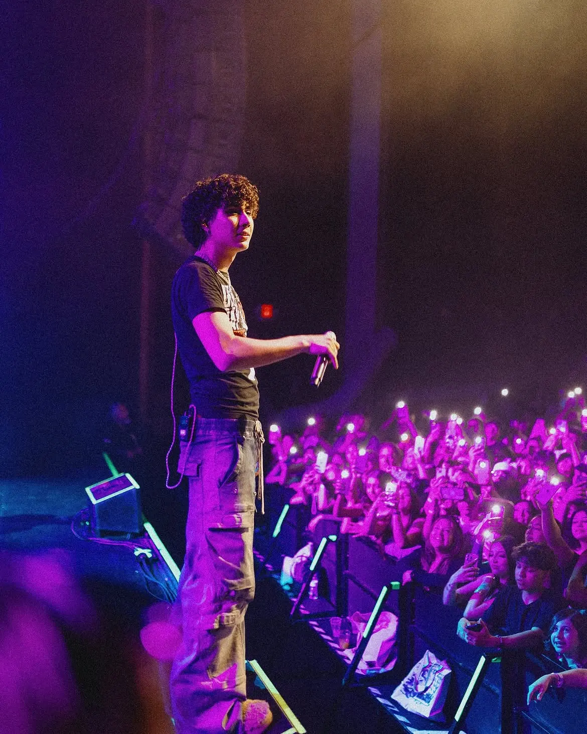 Tucson — stood at the stage edge, the seated floor lit purple below